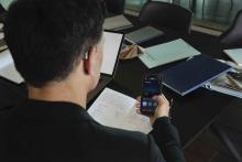 Man with hearing aids sitting at a desk and using a smartphone