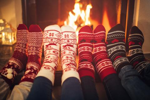 Four pairs of sock feet warming in front of a fireplace